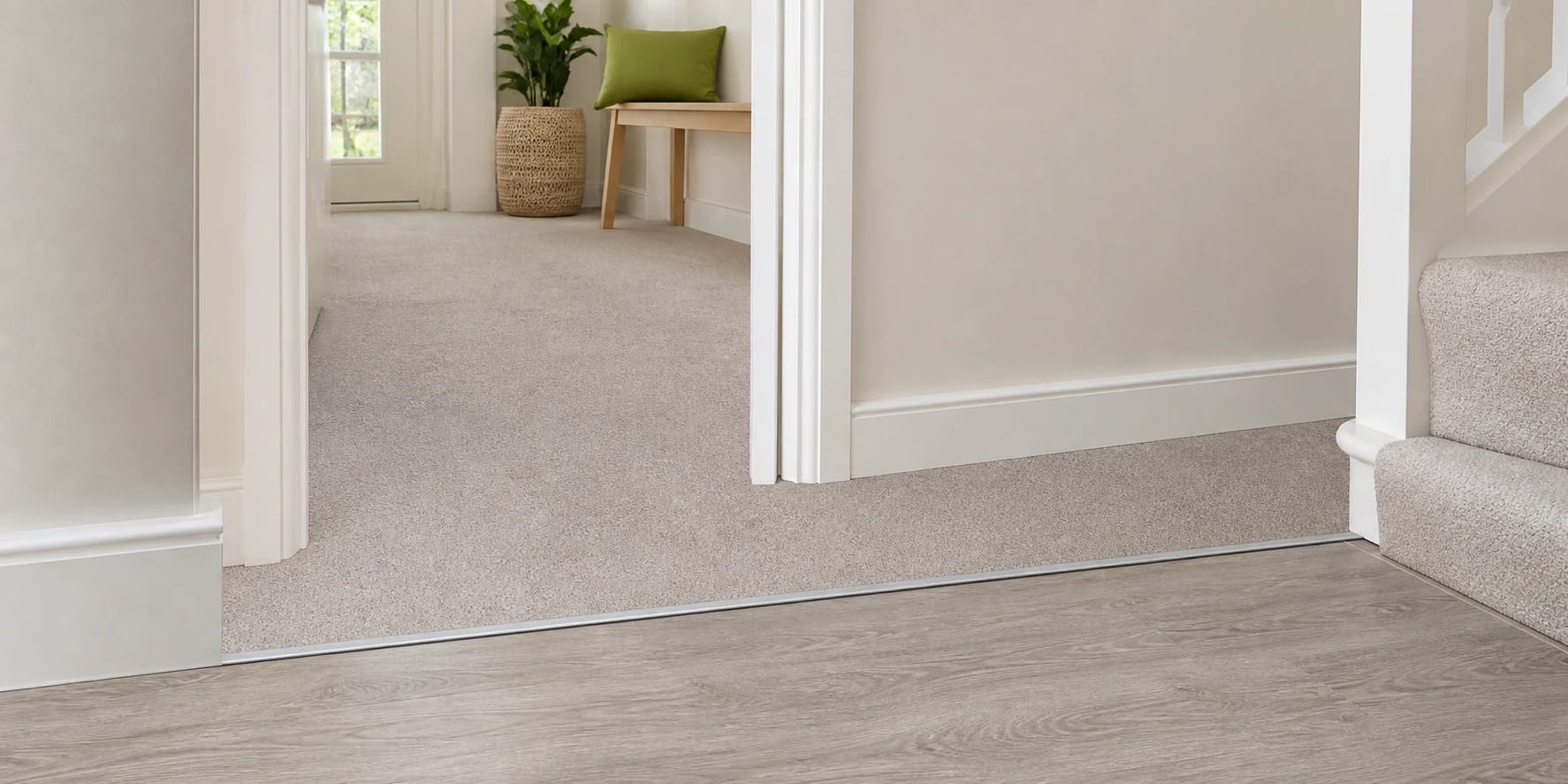 New carpet meeting vinyl flooring with a neat threshold trim in a tidy home hallway